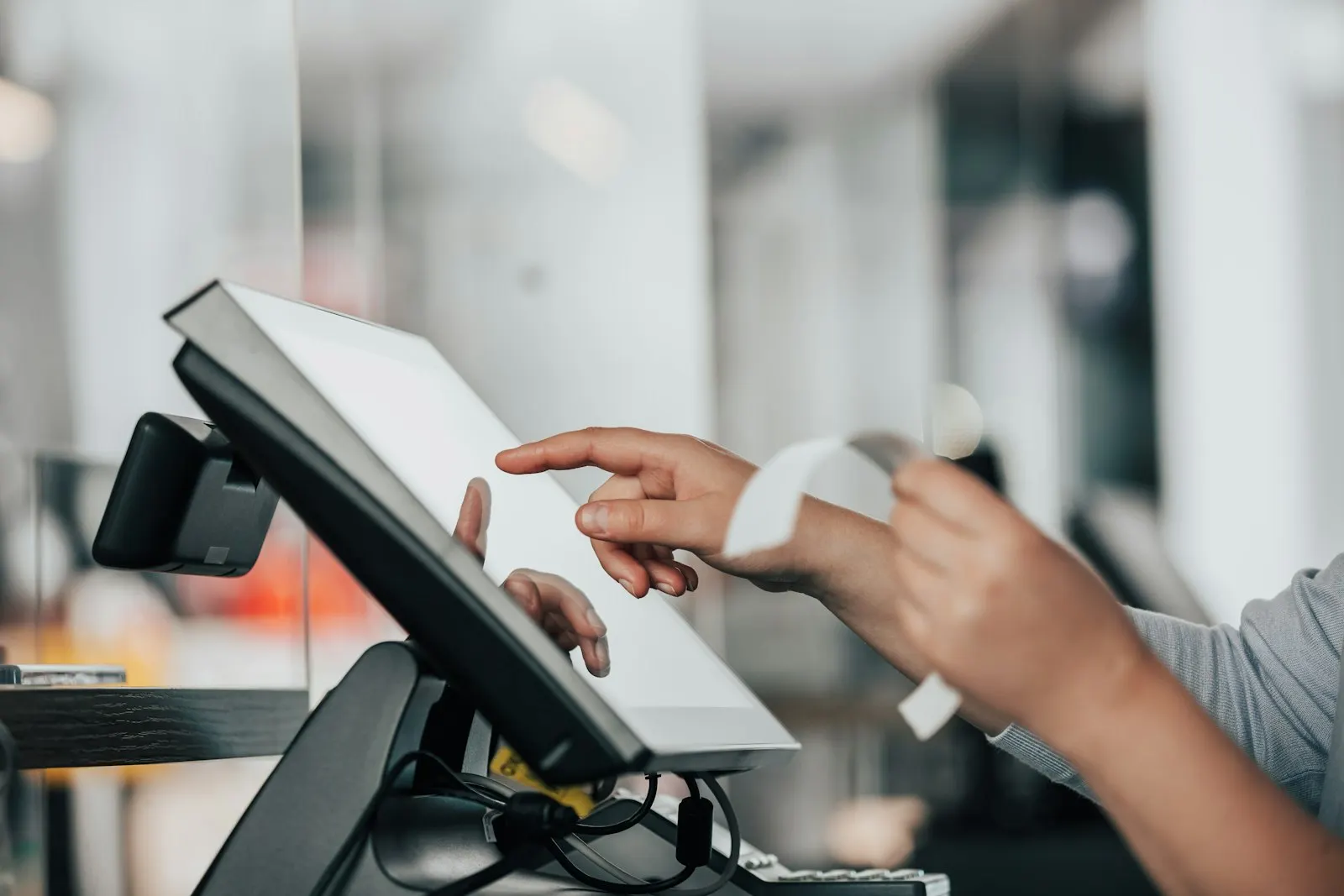 A shopkeeper using a touch screen till at the counter
